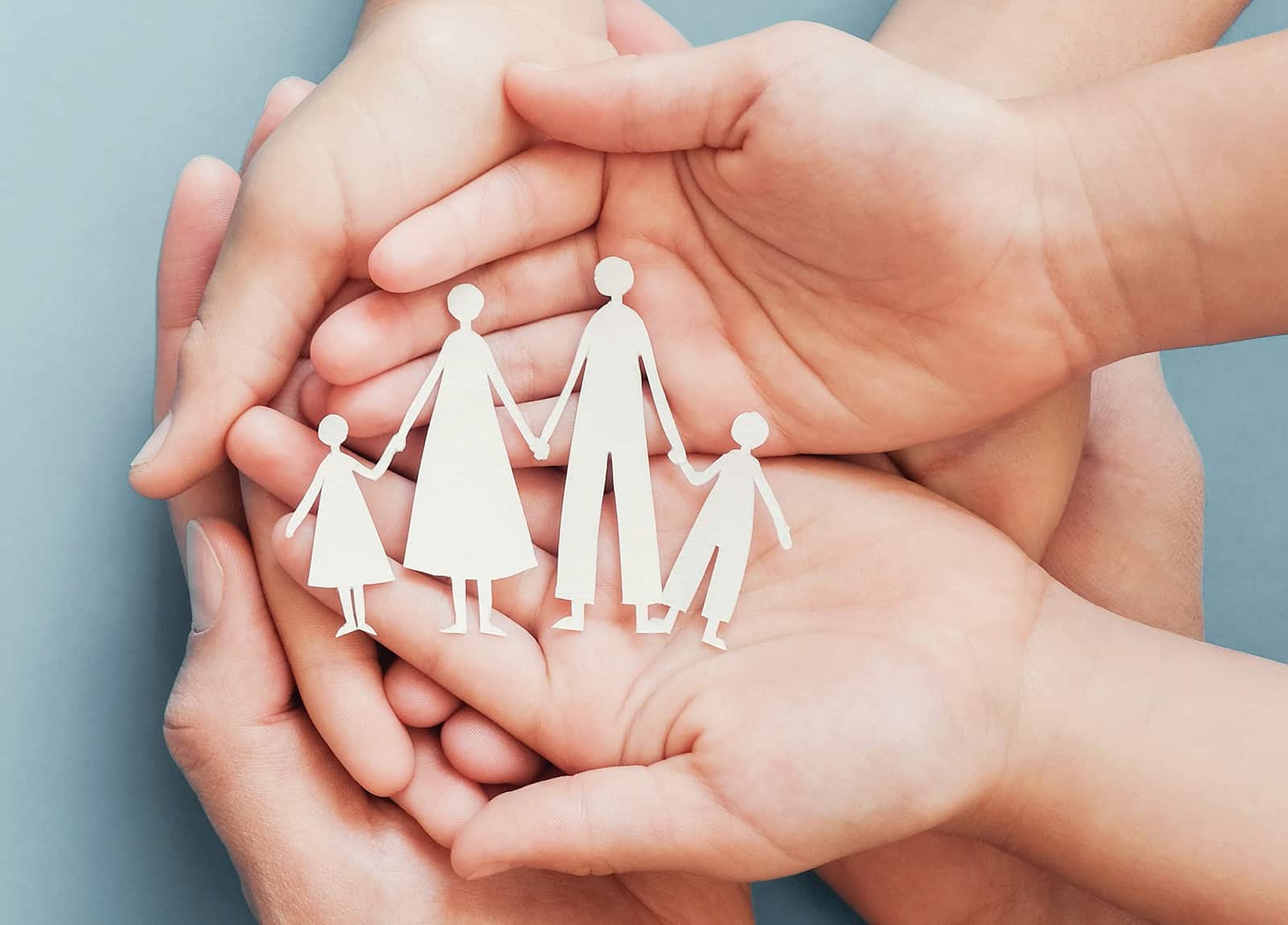 A set of 3 hands holding together a cut-out of a family